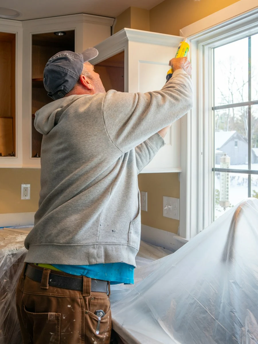 Contractor sealing window trim during a kitchen remodel